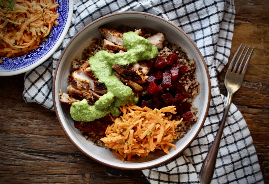 Grilled chicken thighs with carrot slaw and pickled beets atop a fluffy bed of quinoa. Arugula pesto 