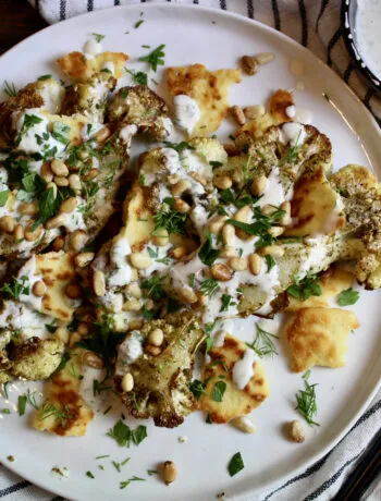 Zataar Roasted Cauliflower topped with Tahini Yogurt Sauce, toasted pine nuts, naan crisps, fresh dill, and parsley. Yum!